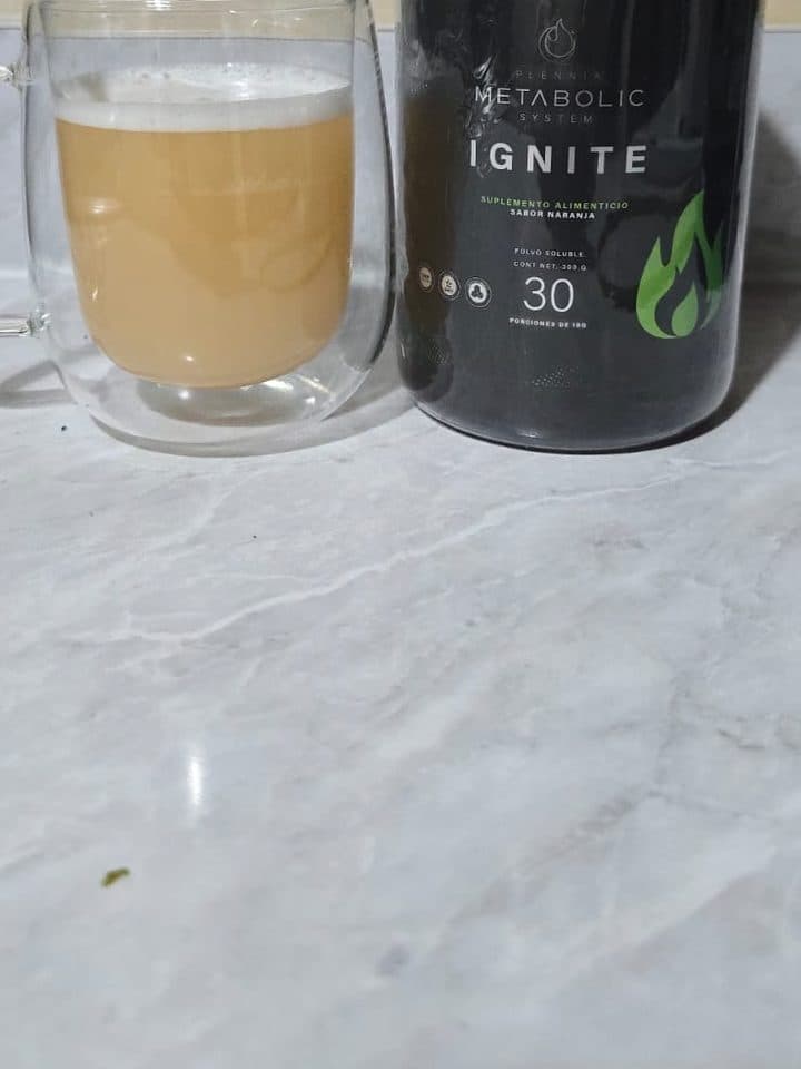 IGNITE ya preparado en un vaso, junto al bote del producto